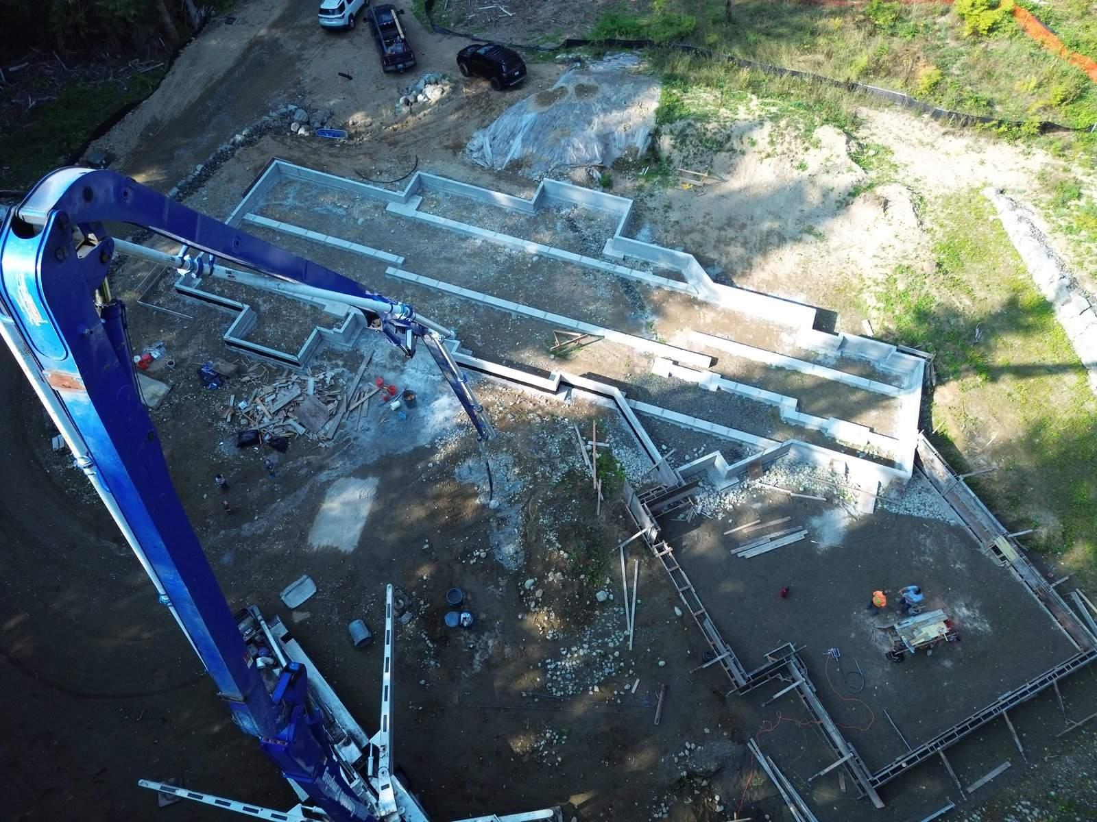 Aerial custom foundation walls with concrete pump boom overhead — HTS Concrete & Construction