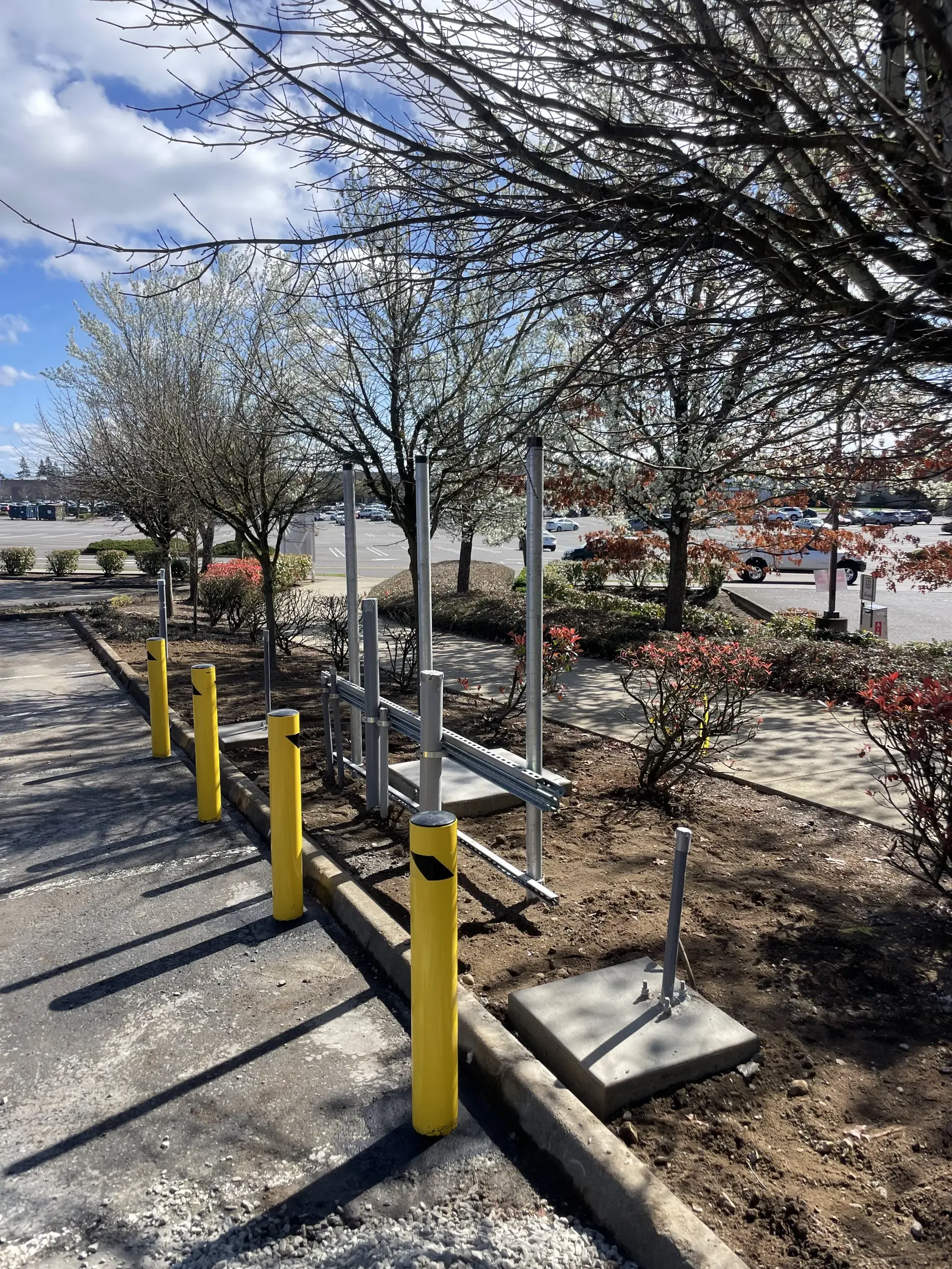 Long utility trench with yellow bollards along the dig