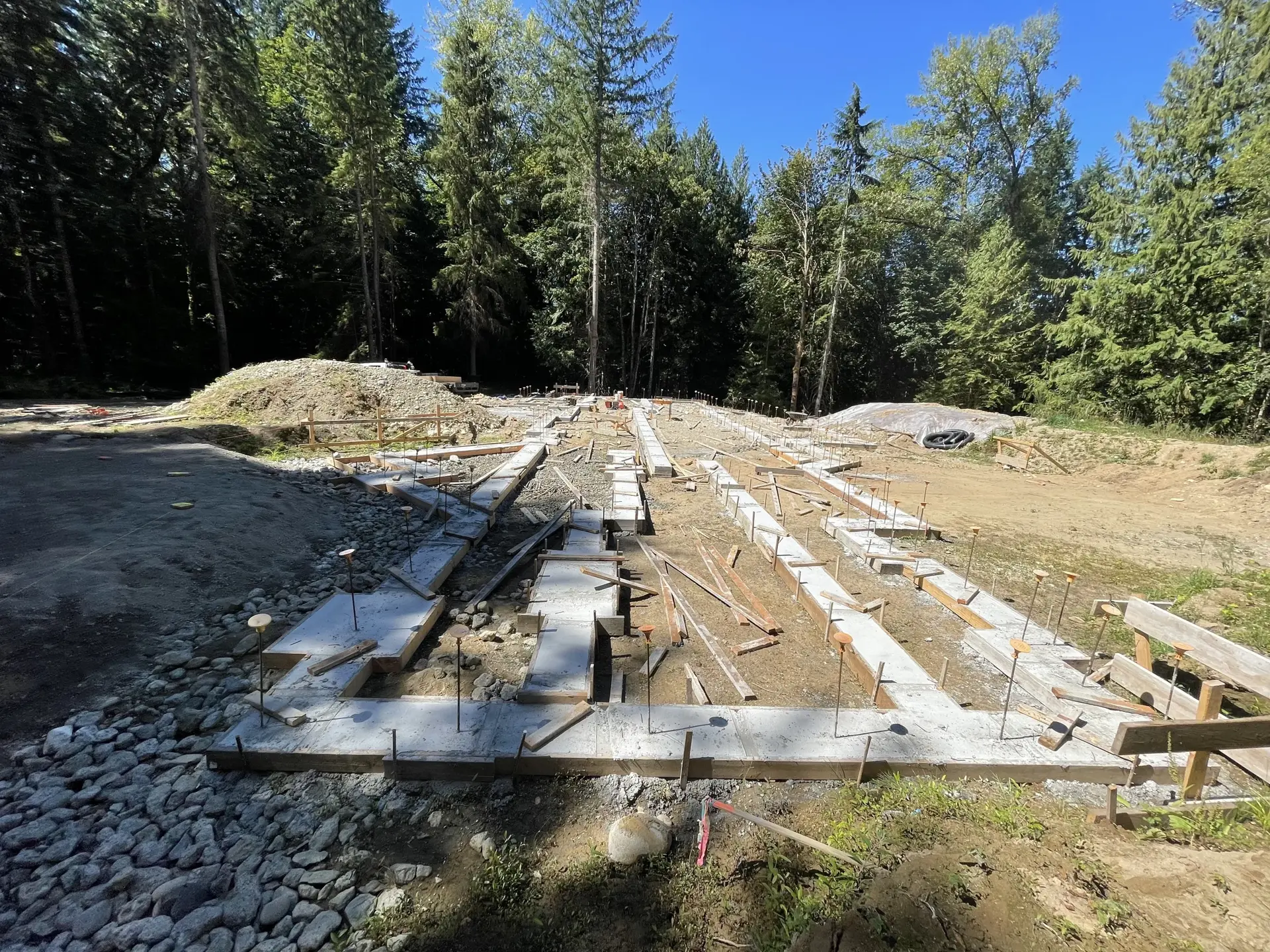 Freshly poured custom foundation footprint in a wooded clearing — HTS Concrete & Construction