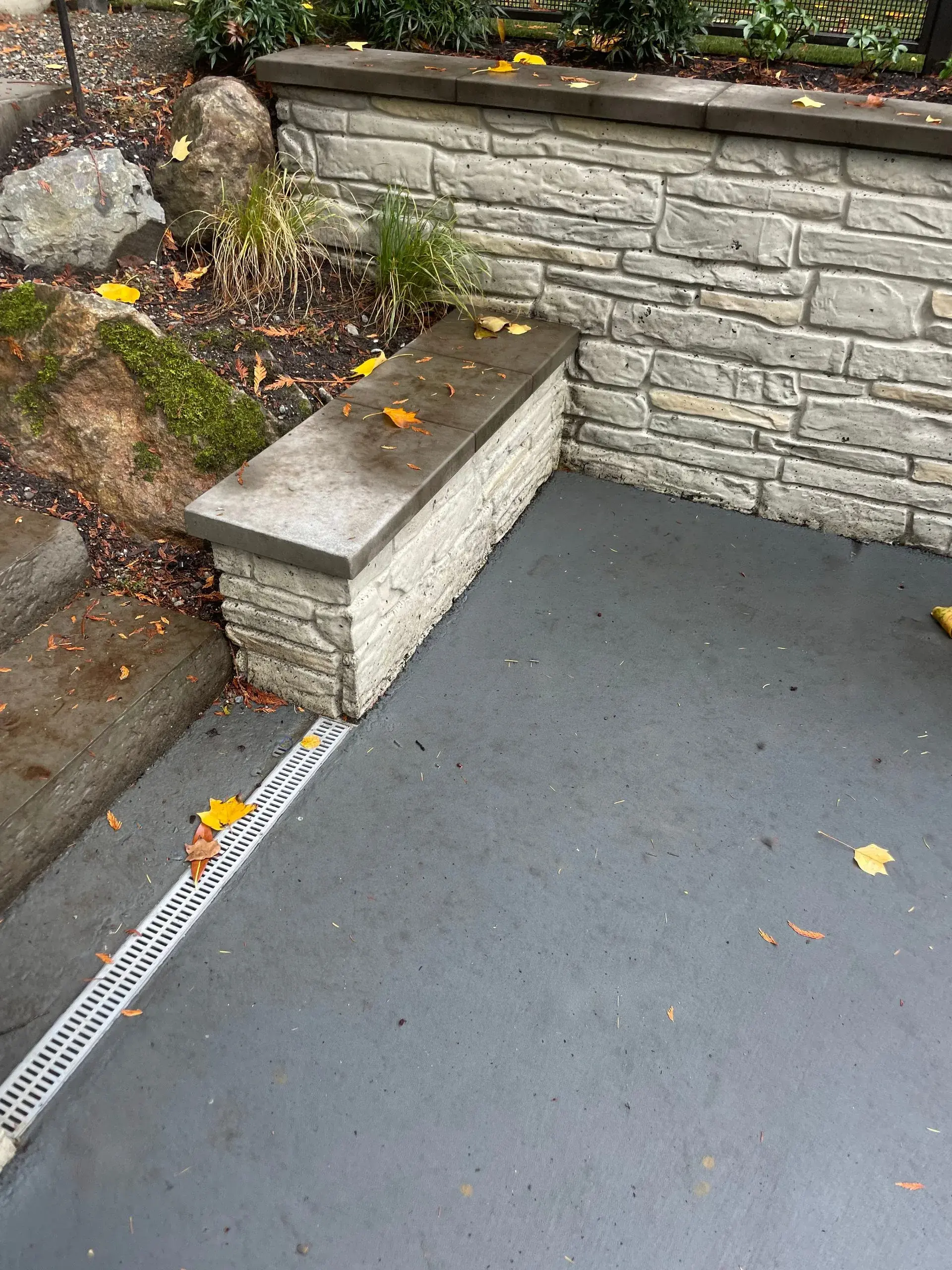 Stone-form concrete wall with built-in bench and trench drain