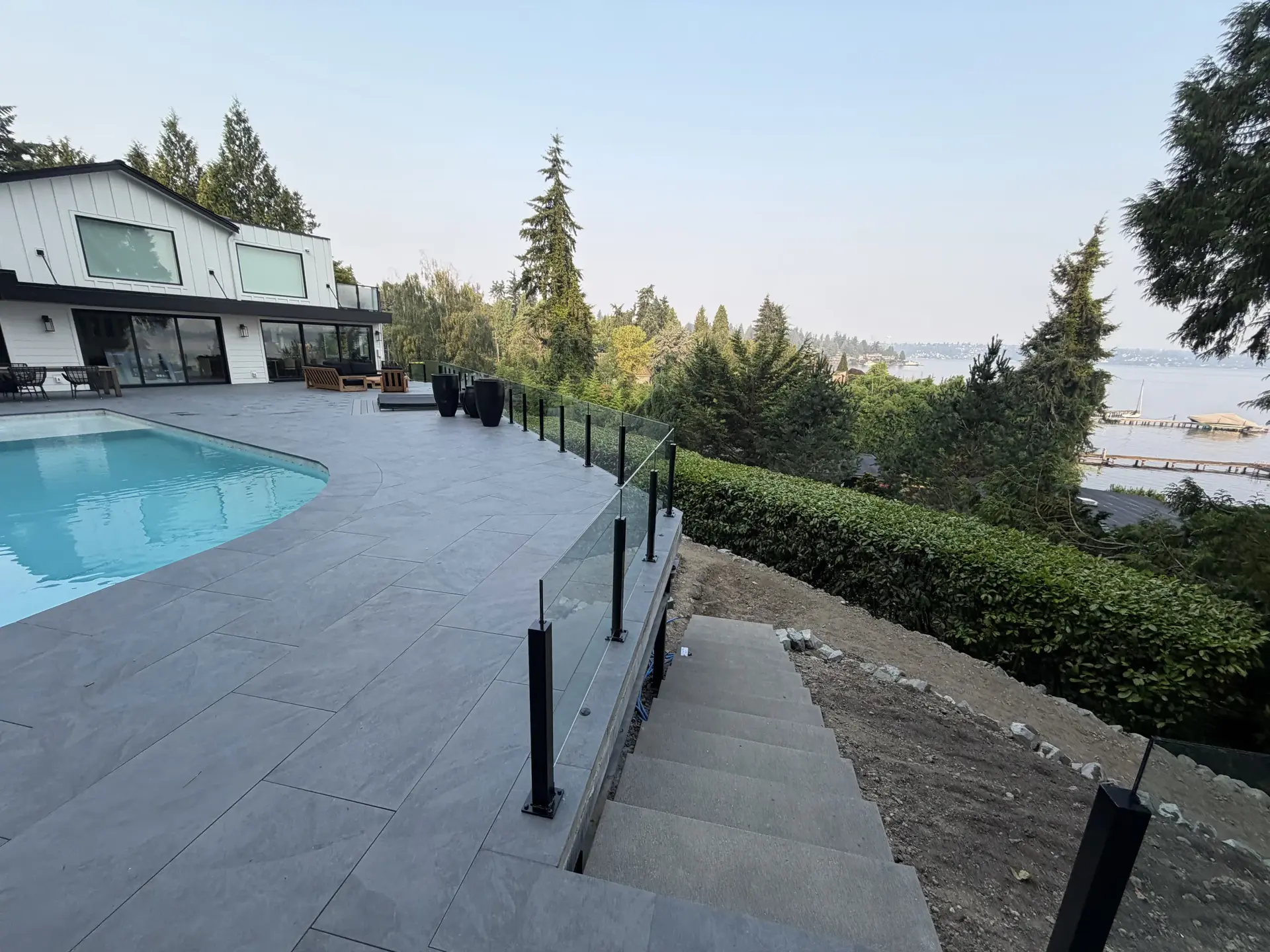 Elevated pool deck with textured pavers and hillside stairs